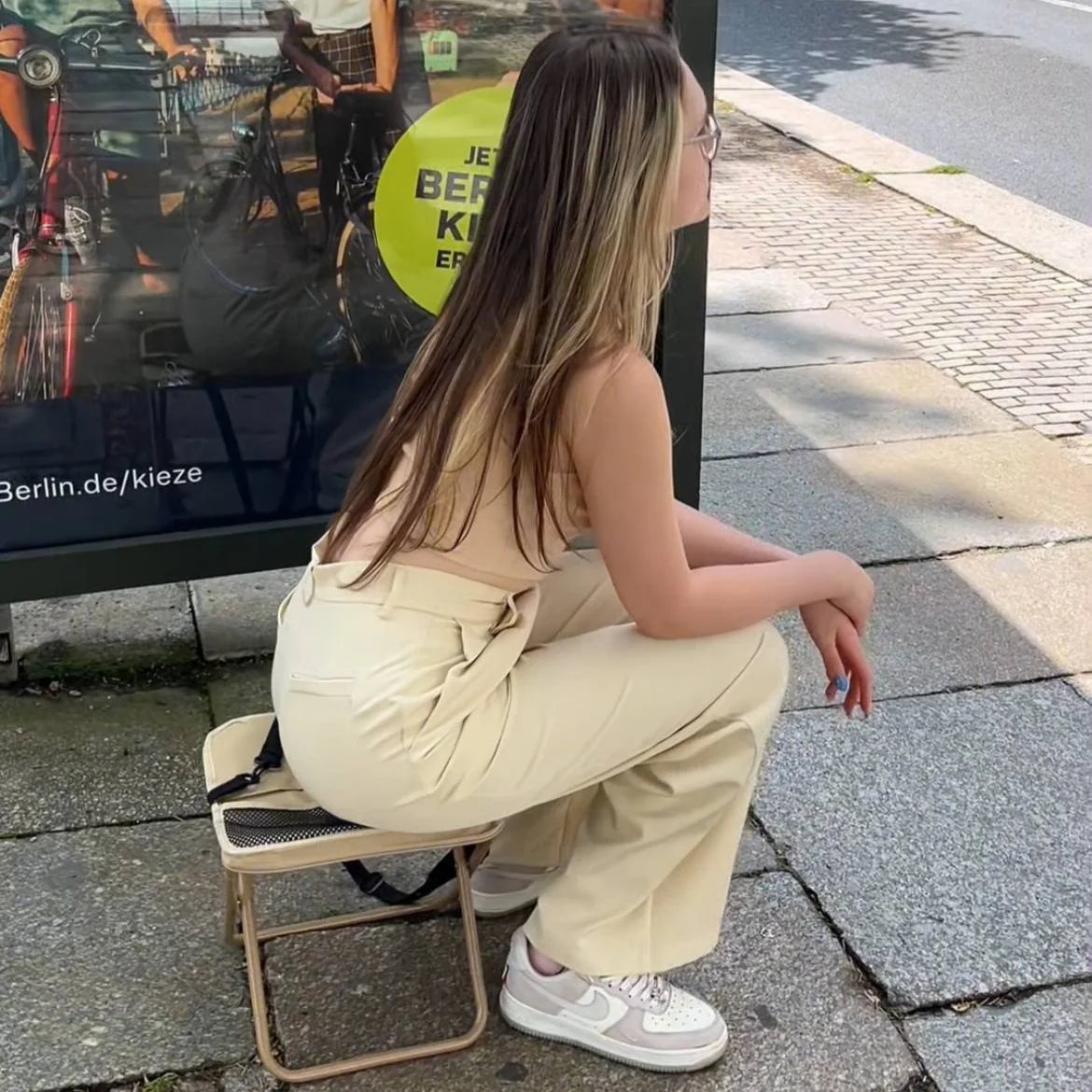 Donna seduta sulla borsa sgabello khaki in città